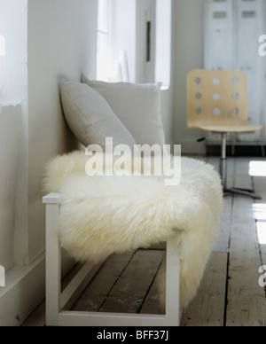 Nahaufnahme der Creme Schaffell Teppich auf Creme Holzbank mit grauen Kissen in moderne Wohnzimmer Stockfoto