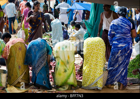 Indische Frauen Bücken kaufen Gemüse aus einem indischen Markt. Puttaparthi, Andhra Pradesh, Indien Stockfoto