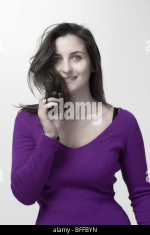 Frau mit langen dunklen Haaren in lila Top isoliert auf weißem Hintergrund Stockfoto