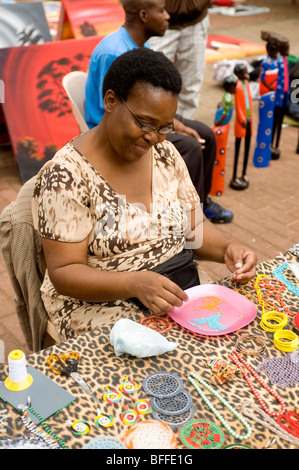 Frau Perle Hals Schnürsenkel zu machen. UShaka Park Street Market. Durban, Südafrika Stockfoto