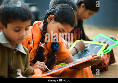 Indian School Kinder sitzen außerhalb ihrer Schule schreiben auf der Schiefertafel. Andhra Pradesh, Indien Stockfoto