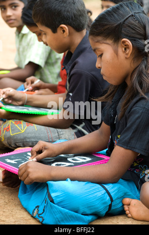 Indian School Kinder sitzen außerhalb ihrer Schule schreiben auf der Schiefertafel. Andhra Pradesh, Indien Stockfoto