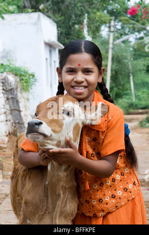 Junge indische Dorfmädchen umarmt eine Kalb in einem indischen Dorf. Andhra Pradesh, Indien Stockfoto