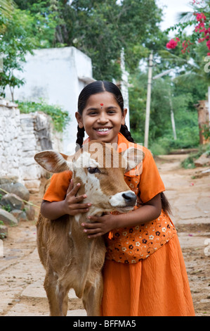 Junge indische Dorfmädchen umarmt eine Kalb in einem indischen Dorf. Andhra Pradesh, Indien Stockfoto