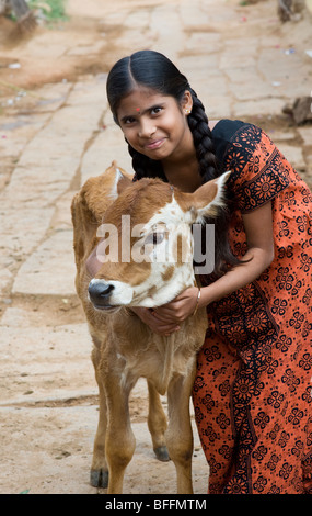 Junge indische Dorfmädchen umarmt eine Kalb in einem indischen Dorf. Andhra Pradesh, Indien Stockfoto