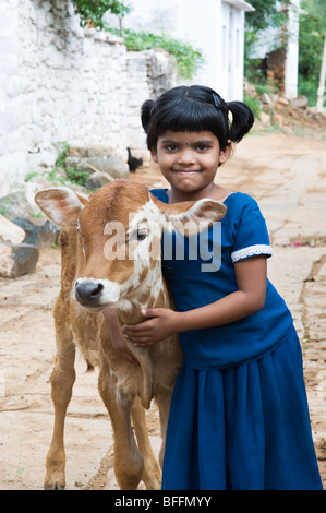 Junge indische Dorfmädchen umarmt eine Kalb in einem indischen Dorf. Andhra Pradesh, Indien Stockfoto