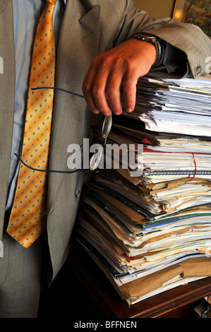 Geschäftsmann, stützte sich auf einen Stapel Papiere, überarbeiteten Büroangestellten oder Manager mit Stapel von Dokumenten Stockfoto