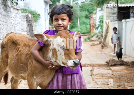 Junge indische Dorfmädchen umarmt eine Kalb in einem indischen Dorf. Andhra Pradesh, Indien Stockfoto