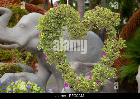 Elefant Skulptur und Herzförmige ausgebildet blühende Laub an Suan oder NongNooch Nong Nooch Tropical Botanical Garden Resort, Pattaya, Thailand Stockfoto