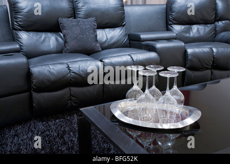 schwarze executive Heimkino Ledersessel mit Weingläsern auf Tablett am schwarzen Tisch Stockfoto
