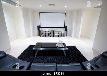 Heimkino-Raum mit schwarzen Ledersesseln liege, schwarzen Teppich und Tisch mit Weingläsern Stockfoto