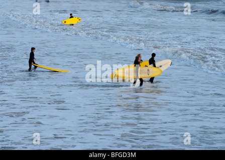 Surfer tragen ihren Brettern ins Meer in Boscombe, Bournemouth. Boscombe ist Heimat von Europas erste künstliche Surf-Riff. Stockfoto