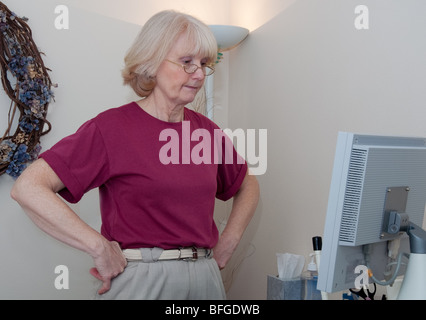 Mittleren Alters medizinisches Fachpersonal steht mit Händen auf den Hüften in einer medizinischen Einstellung mit Ultraschallgerät. Stockfoto