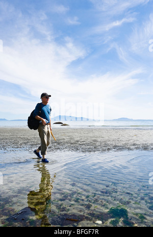 Ein reifer Mann zu Fuß auf einem Strand am Point Whitehorn Marine Reserve, Whatcom County, Washington, USA. Stockfoto