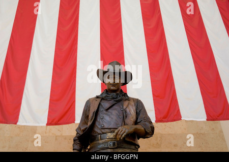 Statue von John Wayne vor einer amerikanischen Flagge befindet sich im Terminal an John Wayne Airport in Orange County, CA Stockfoto