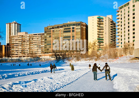 Junges Paar halten Hände und Eislaufen auf dem Assiniboine River Trail in Winnipeg, Manitoba, Kanada Stockfoto