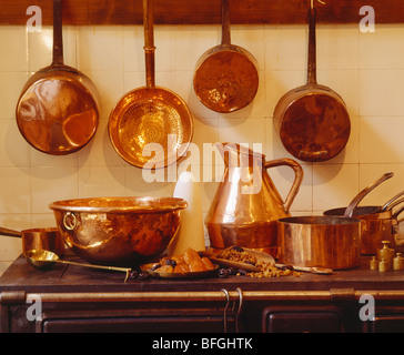 Nahaufnahme der alten Kupfer Pfannen auf Rack über Kupfer Pfanne und Krug auf Herd Stockfoto