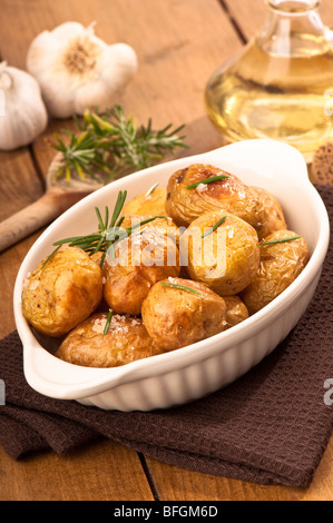 Bratkartoffeln mit Rosmarin Kräuter mit Knoblauch und Olivenöl im Hintergrund Stockfoto