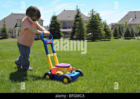 Kleiner junge Rasen zu mähen, mit Spielzeug Mäher, King City, Ontario Stockfoto