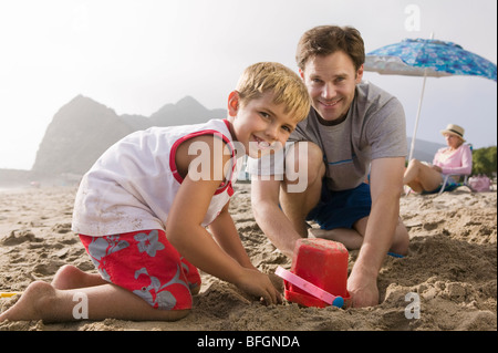 Vater Gebäude Sandburg mit Sohn am Strand Stockfoto