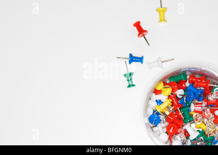 Mehrfarbige Push-Pins verstreut durch Push Pin Jar auf Tisch, Draufsicht, Nahaufnahme Stockfoto