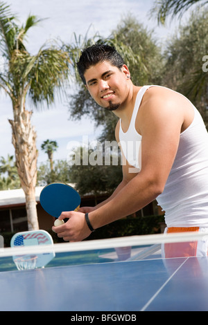 Junger Mann spielen Tischtennis, Swimmingpool Stockfoto