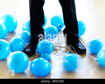 das Unternehmer Beine verstrickt mit deflationierten Luftballons Stockfoto