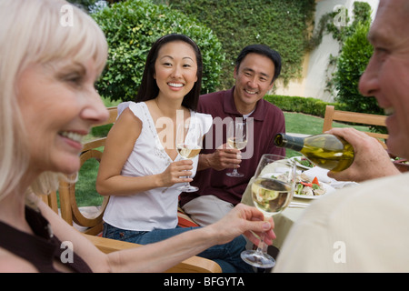 Zwei Paare trinken Wein im Garten Stockfoto