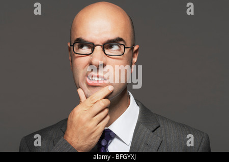 Glatze Geschäftsmann eine Brille mit Hand am Kinn, so dass lustige Gesicht Stockfoto