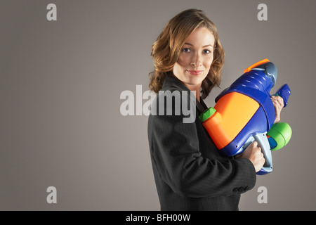 Lächeln, Geschäftsfrau, stehen, halten Wasserpistole, Seitenansicht Stockfoto