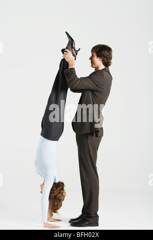 Junge Unternehmer halten Beine Kollegin stehend auf Hände, Profil Stockfoto