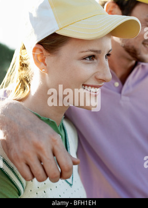 Zwei junge Golfer auf Platz, konzentrieren sich auf lächelnde Frau Stockfoto