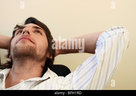 Man lehnt sich zurück auf den Stuhl mit Händen hinter dem Kopf. Stockfoto