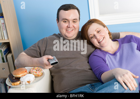 Paar vor dem Fernseher auf Sofa mit Übergewicht Stockfoto