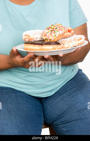 Mittleren Erwachsenenalter übergewichtig Frau Halteplatte mit Donuts. Stockfoto