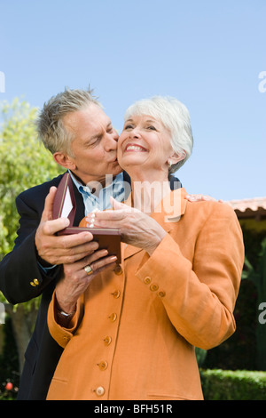 Ältere Mann küssen Frau auf die Wange und gibt vorhanden Stockfoto
