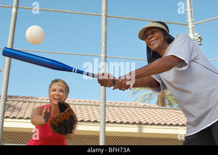 Ältere Frau schlagen Softball mit anderen Frau Fang Stockfoto