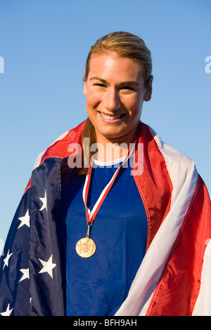 Sportlerin, die in amerikanische Flagge mit goldenen Medaille am Hals gewickelt Stockfoto