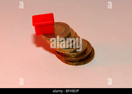 Allgemeine Finanz- und Gehäuse Bild mit Monopol Haus und Haufen von Pfund-Münzen Stockfoto