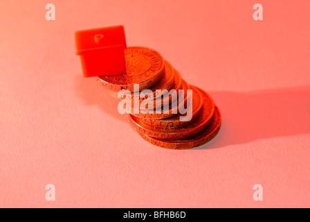 Allgemeine Finanz- und Gehäuse Bild mit Monopol Haus und Haufen von Pfund-Münzen Stockfoto