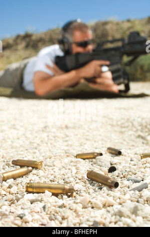 Mann mit dem Ziel Maschinengewehr am Schießplatz, Kugeln im Vordergrund im Fokus Stockfoto