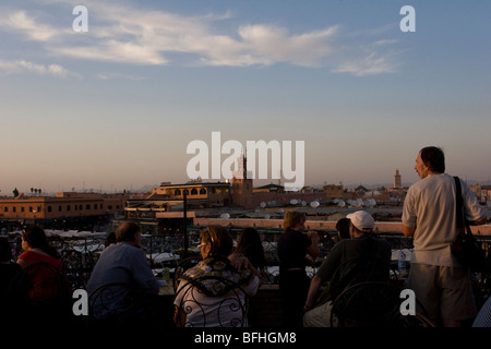 Touristen sehen Djemaa el-Fna, dem zentralen Platz in Marrakesch, heute ein UNESCO-Weltkulturerbe, von einer Dachterrasse. Stockfoto