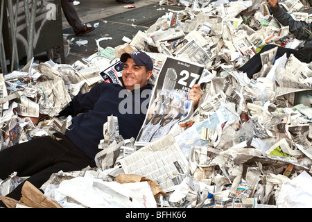 jubelnde lächelnd Yankee Fan zurücklegt hält eine Festschrift Zeitung & halb begraben in einem Erdhügel zerrissenes Papier auf NY Straße Stockfoto