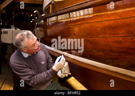 Mann Malerei traditionellen Segelboot auf die Jäger Erbe-Flotte auf den Norfolk Broads Stockfoto