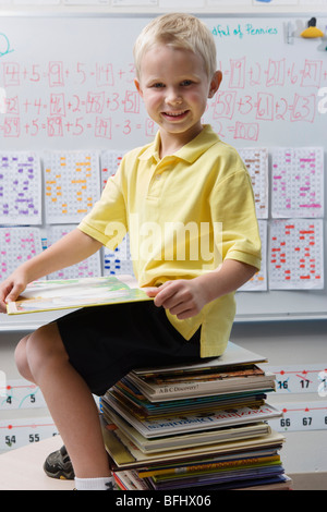 Schüler sitzen auf einem Stapel Bücher
