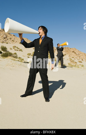 Zwei Geschäftsleute mit Megaphonen in Wüste Stockfoto