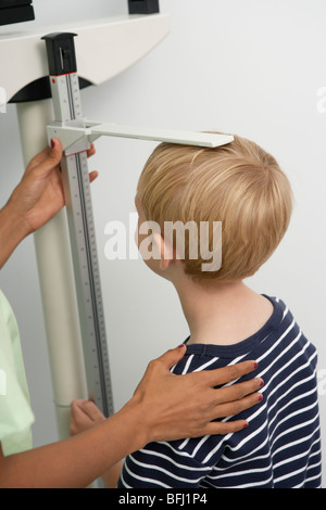 Junge weibliche Krankenschwester, die Messung der Höhe des jungen Stockfoto