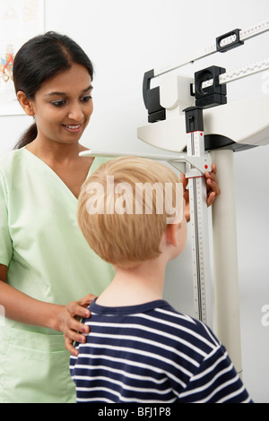 Junge weibliche Krankenschwester, die Messung der Höhe des jungen Stockfoto