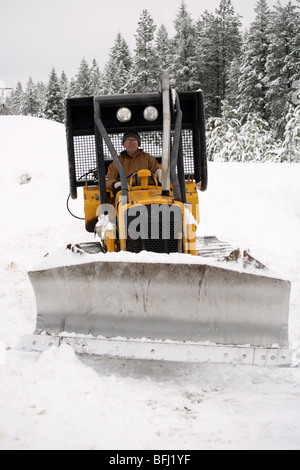 Senioren Pflügen Schnee in eine Planierraupe Bagger. Stockfoto