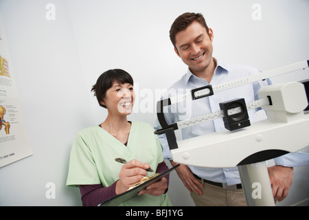 Mann auf Waagen neben Krankenschwester im Krankenhaus Stockfoto